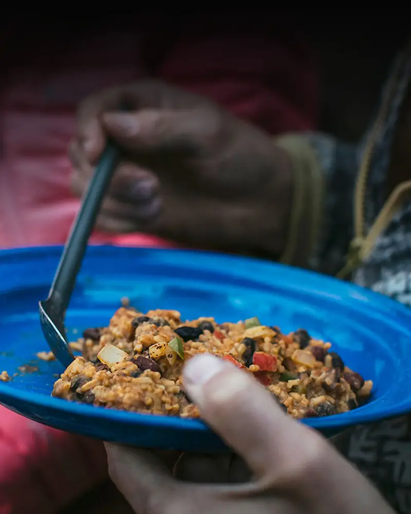 Woman eating a hot meal from a bowl in the back of a truck