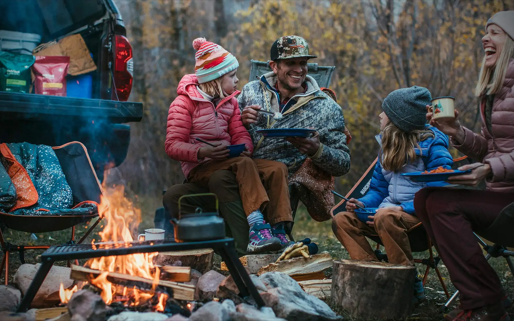 Family eating Nutrient Survival meals around a campfire at dusk